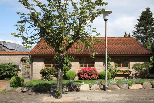 uma casa com uma árvore em frente em Ferienhaus Weingarten em Bad Fallingbostel