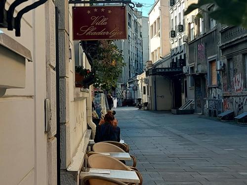 deux personnes assises sur des chaises dans une rue vide dans l'établissement Villa Skadarlija, à Belgrade