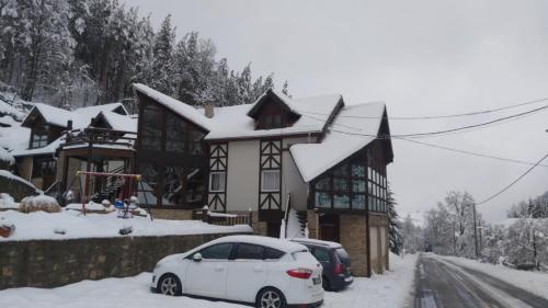 una macchina bianca parcheggiata di fronte a una casa con neve di Ski hotel DOBRODOLAC a Kopaonik