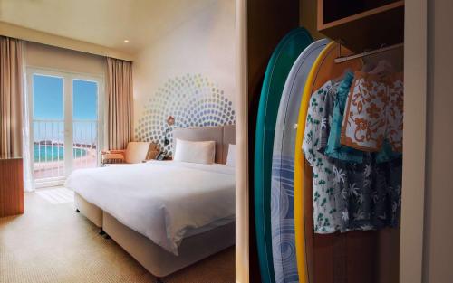 Habitación de hotel con cama y tabla de surf en Rove La Mer Beach, Jumeirah, en Dubái