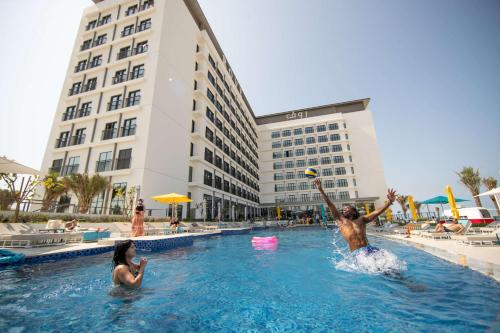 dos personas jugando en la piscina de un hotel en Rove La Mer Beach, Jumeirah, en Dubái