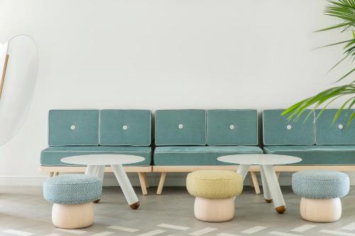 a green couch with two tables and two stools at ME Sitges Terramar in Sitges