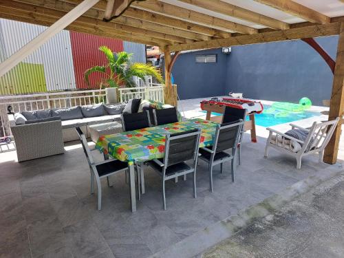 een patio met een tafel en stoelen en een zwembad bij Chambres d'hôtes dans Villa à Chateauboeuf in Fort-de-France