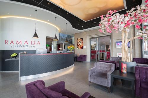 una hall con sedie viola e una reception di Ramada The Hague Scheveningen a Scheveningen