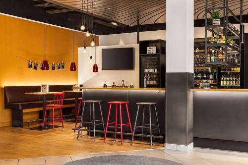 - un bar avec tabourets de bar rouge et télévision dans l'établissement Vienna House Easy by Wyndham Neckarsulm, à Neckarsulm