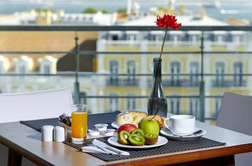 un tavolo con un piatto di cibo e un vaso con un fiore di Luna Esperanca Centro Hotel a Setúbal