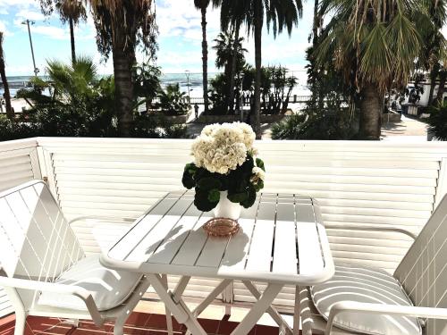 une table et des chaises blanches avec un vase de fleurs dans l'établissement Sitges Seafront Ribera Apartment, à Sitges