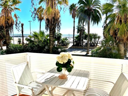 d'une table et de deux chaises sur un balcon avec des palmiers. dans l'établissement Sitges Seafront Ribera Apartment, à Sitges