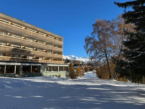 un gran edificio en la nieve frente a una montaña en Hotel Belmont, en Crans-Montana