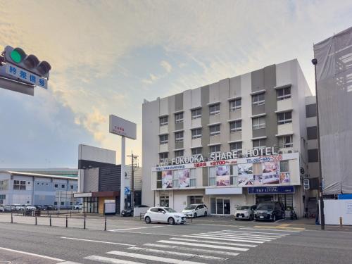 un gran edificio con coches estacionados en un estacionamiento en Fukuoka Share Hotel, en Fukuoka