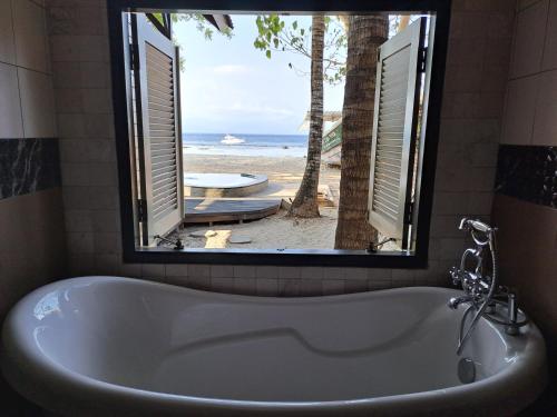 eine Badewanne im Bad mit Blick auf den Strand in der Unterkunft Beach House Penida in Nusa Penida