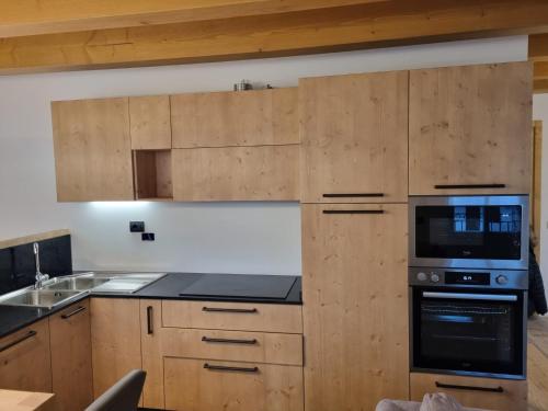 een keuken met houten kasten en een fornuis met oven bij Appartamento Vale e Schena Cortina 4 posti letto in San Vito di Cadore