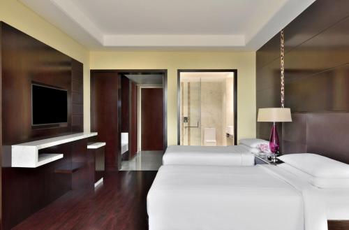 a hotel room with two beds and a tv at Jaipur Marriott Hotel in Jaipur