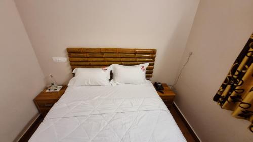 1 cama con 2 almohadas en una habitación pequeña en The Alpine Inn, en Gūdalūr