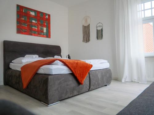 Un dormitorio con una cama con una manta naranja. en AMAO-Brown I 85qm I Central Location I King-Size Bed I Private Parking I Near Storchenturm, en Lahr