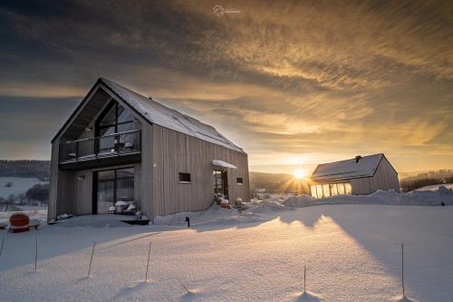 un fienile nella neve con il tramonto sullo sfondo di Bieszczadzka Stodoła a Ustrzyki Dolne