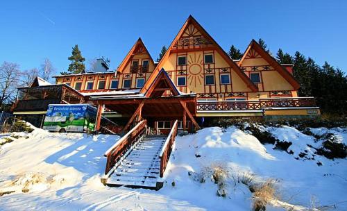 una grande casa in legno con neve di fronte di Hotel Sluníčko a Ostravice