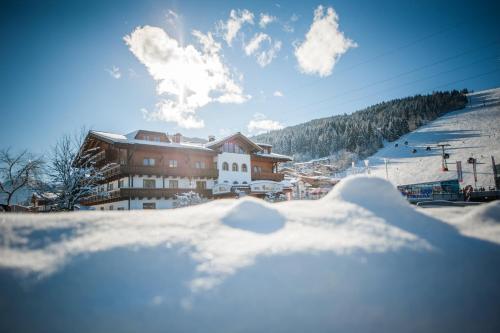 ein schneebedecktes Gebäude vor einem Skigebiet in der Unterkunft Alpines Gourmet Hotel Montanara in Flachau