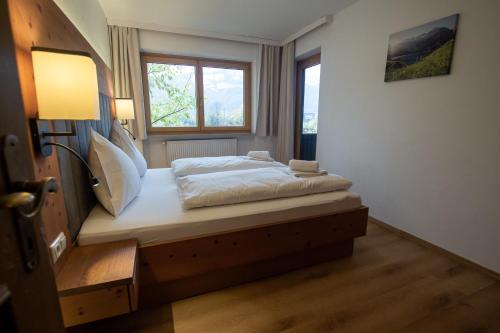 una camera con un letto, un comodino e una finestra di Hochtenn Lodge in Zell am See - Steinbock Lodges a Zell am See