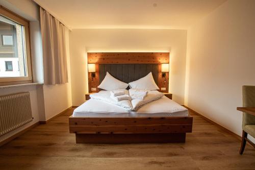 una camera da letto con letto, lenzuola e cuscini bianchi di Hochtenn Lodge in Zell am See - Steinbock Lodges a Zell am See