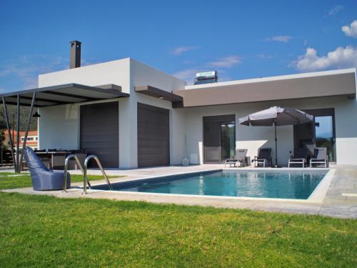 a house with a swimming pool and an umbrella at Nostos Luxury Villas with Private Pool in Nafpaktos in Nafpaktos