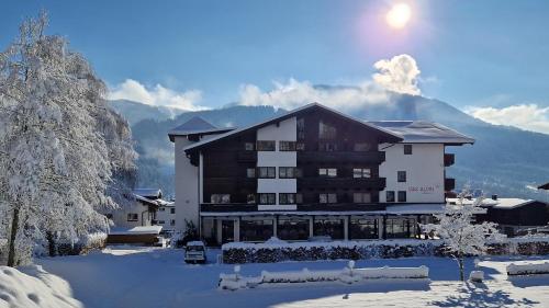 ein großes Gebäude im Schnee mit Bergen im Hintergrund in der Unterkunft Das Alpin - Hotel Garni Guesthouse in Scheffau am Wilden Kaiser