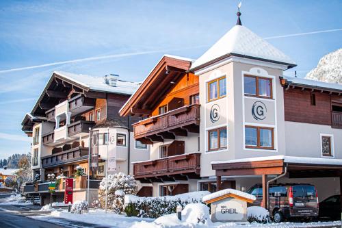 ein Gebäude mit einem Uhrturm im Schnee in der Unterkunft DER GREIL - Wein & Gourmethotel in Söll