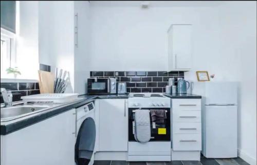 een witte keuken met een vaatwasser en een wastafel bij St Helens - Cosy 1 Bed in Saint Helens