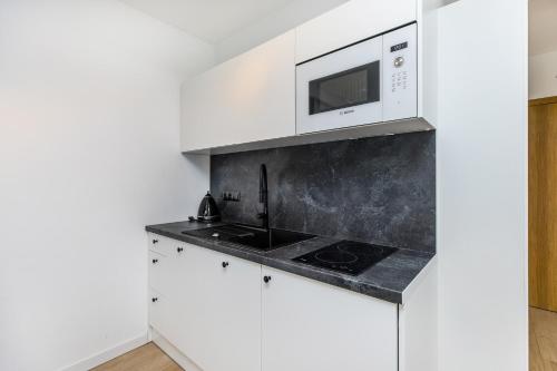 a kitchen with white cabinets and a microwave at Grapa Ski - apartament Białka Tatrzańska in Białka Tatrzanska