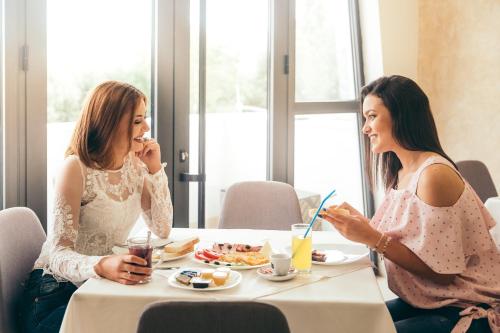 dwie kobiety siedzące przy stole jedzące jedzenie w obiekcie Hotel Dijana w mieście Pirot