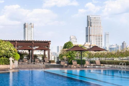 une piscine avec des chaises et des parasols et une vue sur la ville dans l'établissement Sheraton Guangzhou Hotel, à Canton