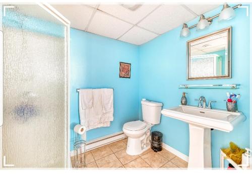 een blauwe badkamer met een toilet en een wastafel bij Leila's Place-Family Deluxe Basement Apartment in Gatineau