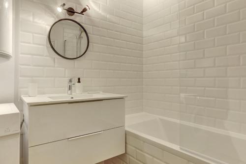 a white bathroom with a sink and a mirror at Le Petit Nid - Apt Lumineux en Hypercentre in Montigny-le-Bretonneux