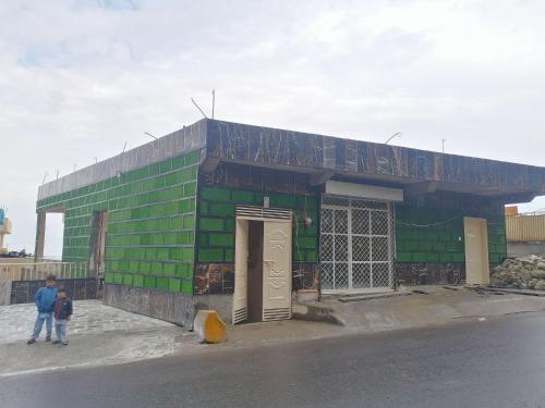 a green building with two people standing in front of it at Navid's Holiday Resort and Hotel, Murree in Ghora Gali