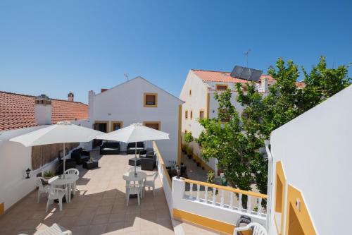 einen Balkon mit Tischen, Stühlen und Sonnenschirmen in der Unterkunft Sol da Vila in Vila Nova de Milfontes