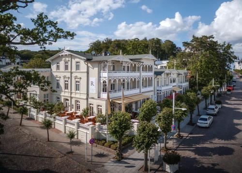 un grand bâtiment blanc dans une rue arborée dans l'établissement ROEWERS Privathotel & Spa, à Sellin