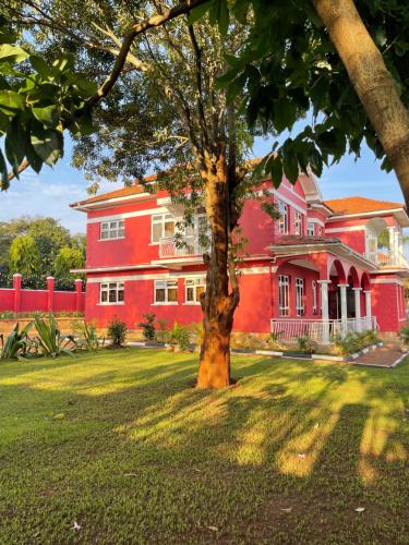 un bâtiment rouge avec un arbre devant lui dans l'établissement The Jewel and the Lake, à Jinja