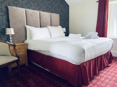 duże łóżko w pokoju hotelowym z krzesłem w obiekcie Merrion Hotel w mieście Llandudno