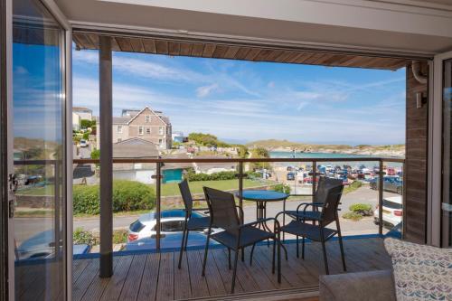 balcón con mesa, sillas y vistas al océano en The Beach House & Porth Sands Apartments, en Newquay