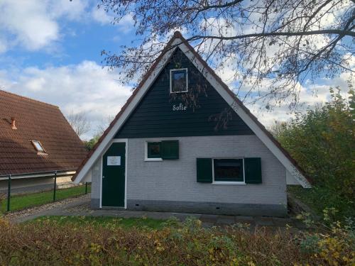 een zwart-wit huis met een groene deur bij Vakantiehuis Sofie Lauwersmeer met sauna in Anjum