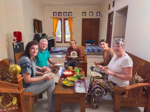 Un gruppo di persone seduti intorno a un tavolo che mangiano cibo di Wildan Homestay a Mangun