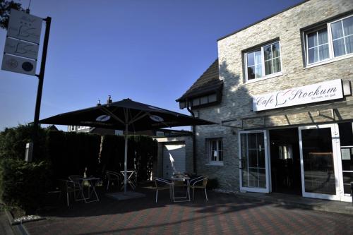 ein Café mit Tischen und Sonnenschirmen vor einem Gebäude in der Unterkunft Boutique Hotel Villa Stockum in Düsseldorf