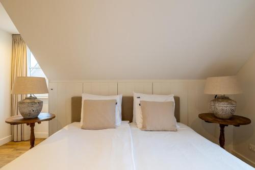 a bedroom with a white bed with two lamps at Villa Zuiderduin in Zoutelande