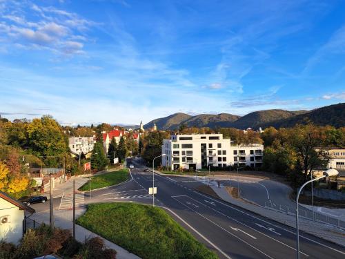 an empty street in a city with buildings and mountains at Alcorso Pension in Banská Bystrica