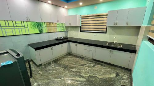 a kitchen with white cabinets and a sink at Welldone Wayanad Holidays in Sultan Bathery