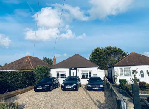 3 voitures garées devant une maison blanche dans l'établissement West Wittering Family Home, à West Wittering