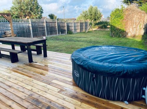 une terrasse en bois avec une table de ping-pong et un bluelatablelatable dans l'établissement West Wittering Family Home, à West Wittering