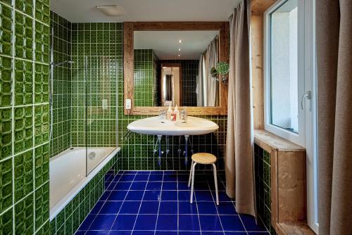 La salle de bains carrelée de couleur verte est pourvue d'un lavabo et d'une baignoire. dans l'établissement Sporthotel Kogler, à Mittersill