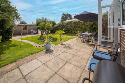 um pátio com uma mesa, cadeiras e um guarda-sol em Solenta em Yarmouth