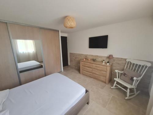 um quarto com uma cama, uma cadeira e uma televisão em Appartement Vacances ZEN em Fréjus